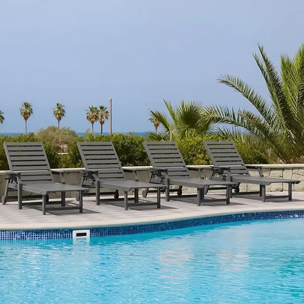 Row of dark grey commercial grade HDPE poly lounge chairs lined up by outdoor pool