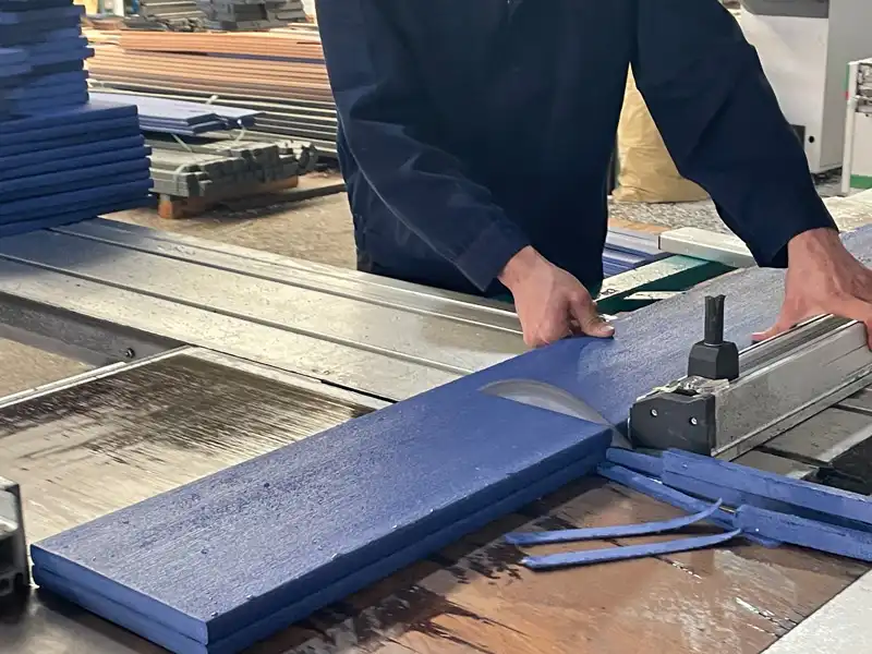Factory worker cutting plastic lumber during HDPE lounge chair component manufacturing