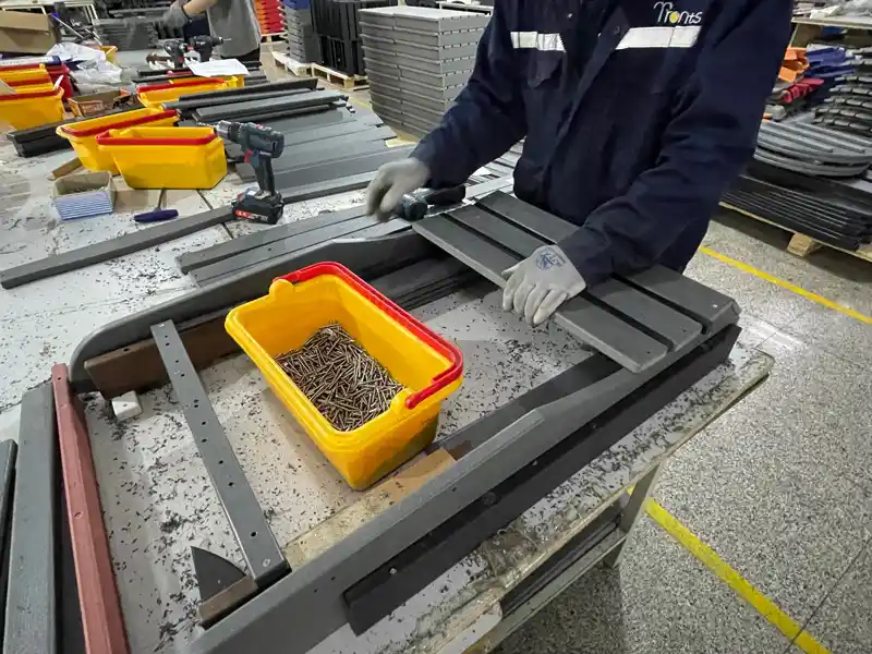 Factory worker assembling HDPE Adirondack chair components on production line for bulk OEM orders