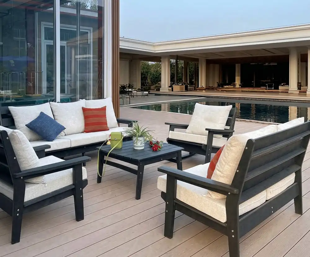 Black HDPE deep seating patio sofa set with thick cushions placed on a resort poolside deck.