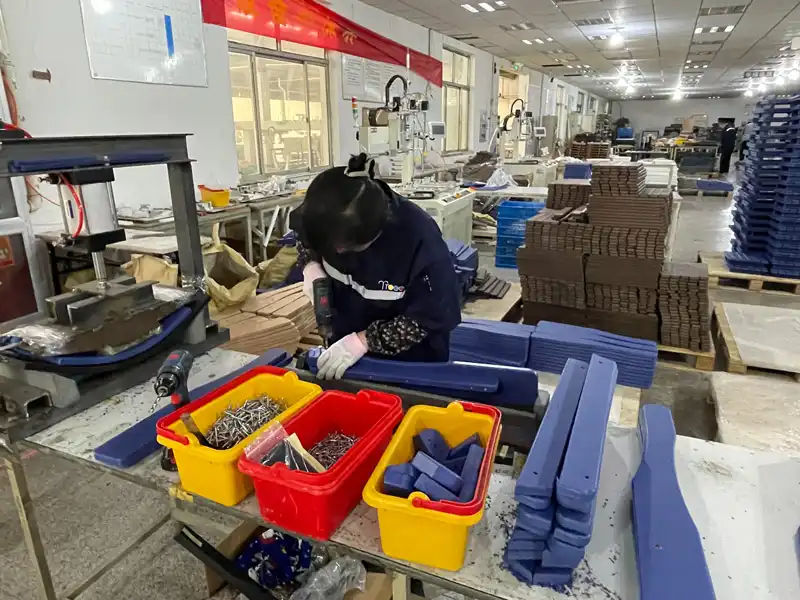 Factory worker assembling blue HDPE furniture components with power tool