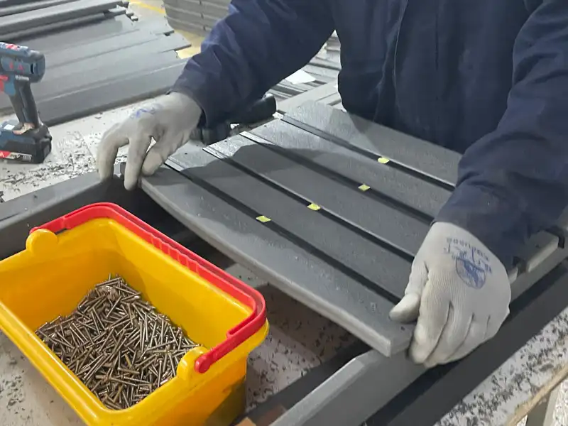 Assembly line worker checking hardware and components at HDPE outdoor furniture factory